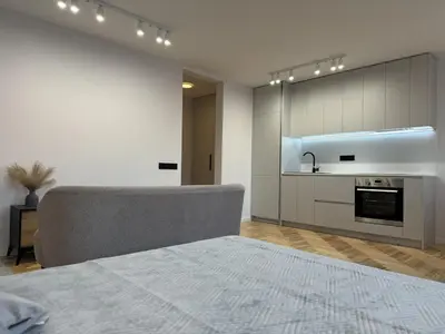 a living room with a couch and a kitchen at Cozy Apartment Near Forest in Kaunas