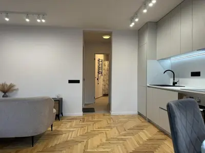 a kitchen with white walls and a wooden floor at Cozy Apartment Near Forest in Kaunas