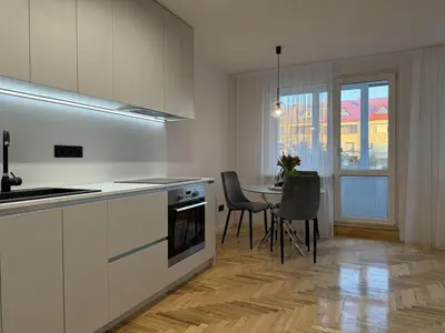 a kitchen with white cabinets and a table with chairs at Cozy Apartment Near Forest in Kaunas