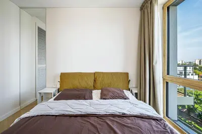 a bedroom with a bed and a large window at Modern city center apartment in Vilnius
