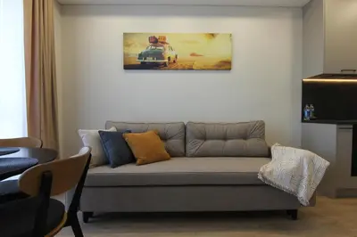 a couch in a living room with a painting on the wall at Warmzy Home - Modern Flat with Free Parking in Vilnius