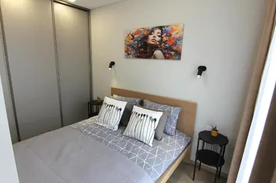 a bedroom with a bed with a painting on the wall at Warmzy Home - Modern Flat with Free Parking in Vilnius
