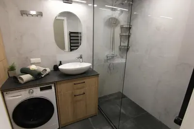 a bathroom with a washing machine and a sink at Warmzy Home - Modern Flat with Free Parking in Vilnius