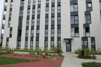 a large white building with black windows at Warmzy Home - Modern Flat with Free Parking in Vilnius