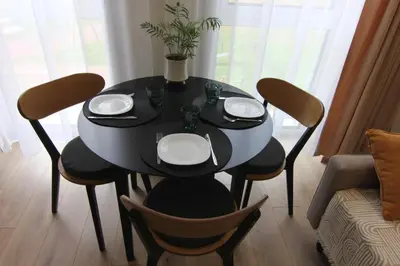 a dining room table with chairs and a black table with plates at Warmzy Home - Modern Flat with Free Parking in Vilnius