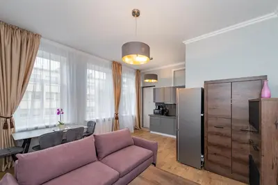 a living room with a couch and a table and a kitchen at Elegant city center apartment with free parking by Polo Aparments in Kaunas