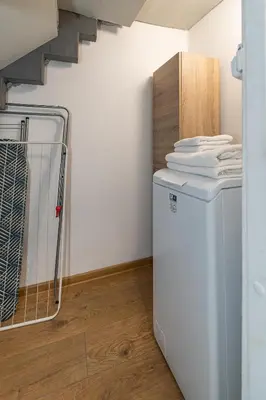 a laundry room with a washing machine and a staircase at Elegant city center apartment with free parking by Polo Aparments in Kaunas