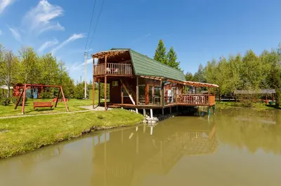 a wooden house on the water with a playground at Sodyba Brazylija in Taraldžiai