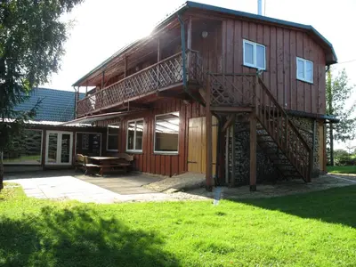 a large wooden house with a large deck at Sodyba Brazylija in Taraldžiai