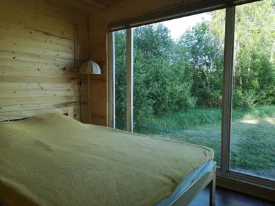 a bedroom with a bed and a large window at Sodyba Brazylija in Taraldžiai