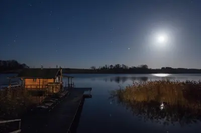 a cabin on a dock on a lake at night at Sodyba Brazylija in Taraldžiai