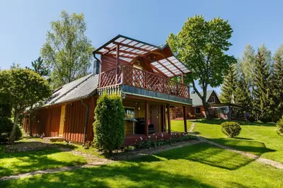 a house with a balcony on top of a yard at Sodyba Brazylija in Taraldžiai