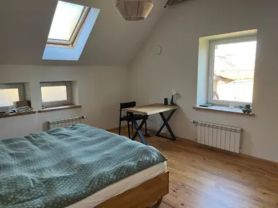 a bedroom with a bed and a desk and windows at The cave in Vilnius