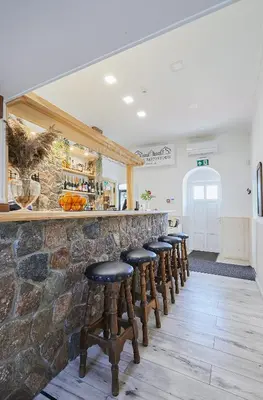 a row of stools at a bar with a stone wall at Arklių Pašto Stotis in Staškūniškis
