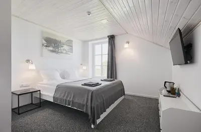 a white bedroom with a bed and a window at Arklių Pašto Stotis in Staškūniškis