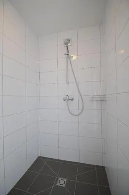a shower in a white tiled bathroom at BHB Hotel in Marijampolė