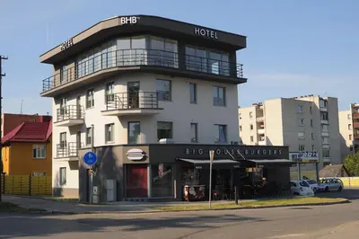 a large white building with a store on the street at BHB Hotel in Marijampolė