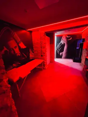 a red room with a bench and a picture of a person at 69 apartaments BDSM in Panevėžys