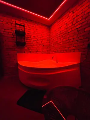 a red bath tub in a room with a brick wall at 69 apartaments BDSM in Panevėžys