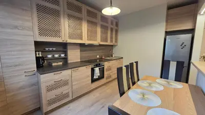 a kitchen with wooden cabinets and a table with chairs at Vytauto Apartments in Šiauliai