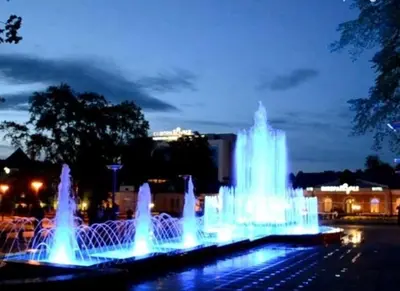 a group of water fountains in a city at night at Victoria Central Apartamentai in Druskininkai