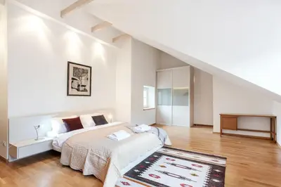 a white bedroom with a bed and a staircase at Saint John Two Bedroom Cottage by Reside Baltic in Vilnius