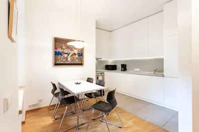a kitchen with white cabinets and a white table and chairs at Saint John Two Bedroom Cottage by Reside Baltic in Vilnius