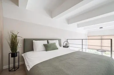 a white bedroom with a large bed and a window at Loft 10 in Vilnius