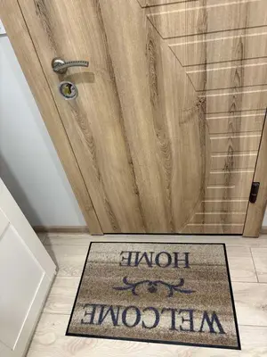 a bathroom door with a welcome mat in front of a shower at Little cocoon at border of old city in Vilnius