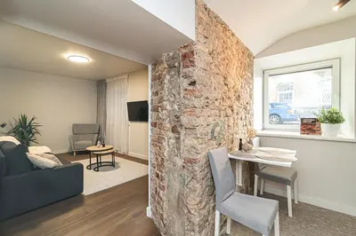 a living room with a stone wall and a table and chair at Cozy flat in Vilnius Old Town in Vilnius