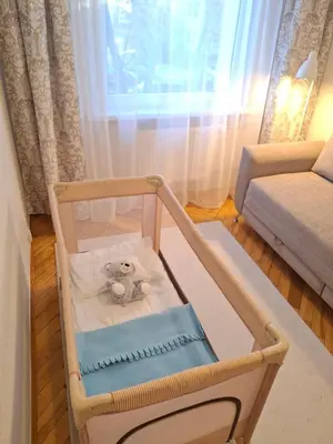 a teddy bear sitting in a crib in a room at Angel Apartment near city centre in Vilnius