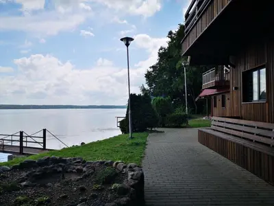 a sidewalk next to a building next to a body of water at Kauno Marių Vilos in Samylai