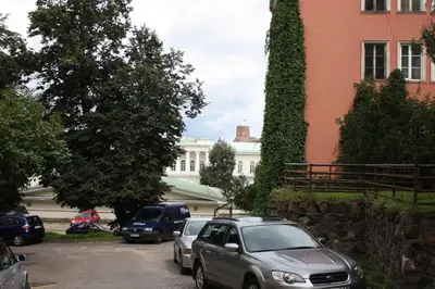 two cars parked in a parking lot in front of a building at 2 bedroom old town apartment with parking in Vilnius
