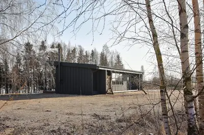 a black building in a field next to trees at The Barn