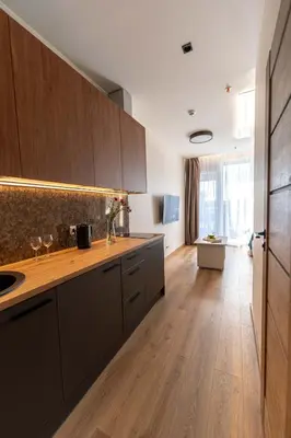 a kitchen with wooden cabinets and a wooden floor at Sky Pool Escape Luxury Apartment in Druskininkai Center in Druskininkai