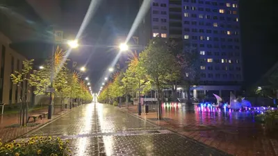 a wet city street at night with lights at Draugystės Apartments - Šiauliai Center in Šiauliai