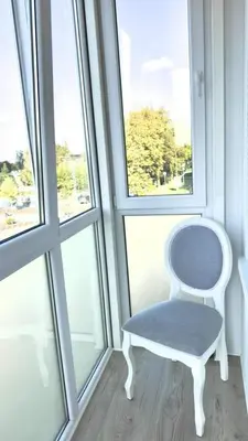 a white chair sitting in front of a window at Draugystės Apartments - Šiauliai Center in Šiauliai