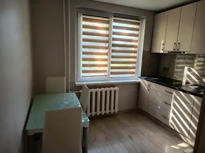 a kitchen with a table and a window with blinds at Vieno kambario butas Šiauliuose in Šiauliai