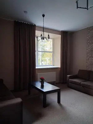 a living room with a table and a couch and a window at Šiluvos Svaja in Šiluva