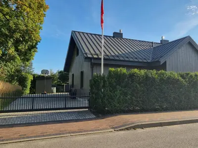 a flag pole in front of a building with a fence at Vandens takas in Birštonas