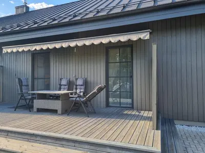 a wooden deck with a table and chairs on a house at Vandens takas in Birštonas