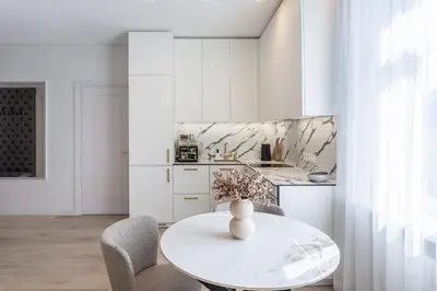 a white kitchen with a white table and chairs at Central Stay Apartments in Šiauliai