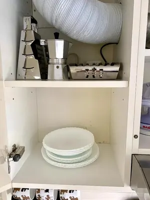 a shelf with a stack of plates in a kitchen at Bright and cozy apartment in the city center with balcony in Šiauliai