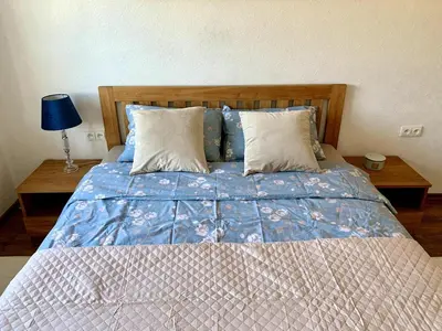 a bed with a blue comforter and two pillows at Bright and cozy apartment in the city center with balcony in Šiauliai