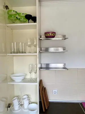 a kitchen with glasses and plates on shelves at Bright and cozy apartment in the city center with balcony in Šiauliai