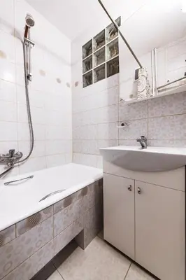 a white bathroom with a sink and a tub at Cozy Apartment in Kaunas with Free Parking. in Kaunas