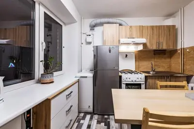 a kitchen with a stainless steel refrigerator and wooden cabinets at Cozy Apartment in Kaunas with Free Parking. in Kaunas