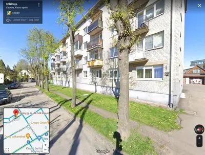 a sign on the side of a street next to a building at Cozy Apartment in Kaunas with Free Parking. in Kaunas