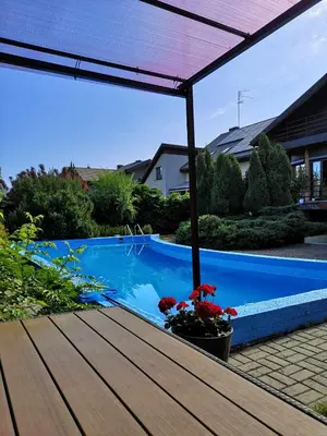 a view of a swimming pool from a patio with an umbrella at Studija viloje-Quiet Apartment 15 min from Airport in Kaunas