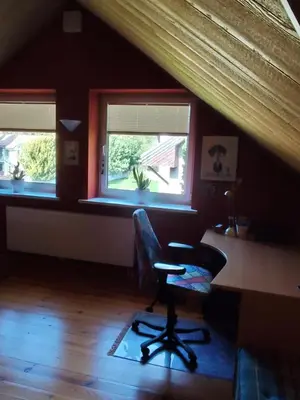 a room with a chair and a desk and two windows at Studija viloje-Quiet Apartment 15 min from Airport in Kaunas